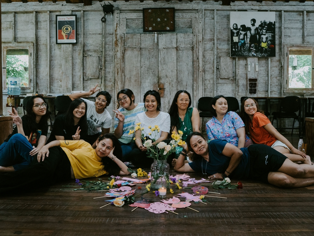 Eine Gruppe von Teilnehmer:innen sitzen und liegen auf dem Boden mit ihren Schattenpuppen an einem Workshop in Indonesien.