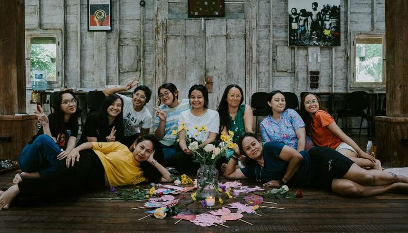 A group of participants sit and lie on the floor with their shadow puppets at a workshop in Indonesia.